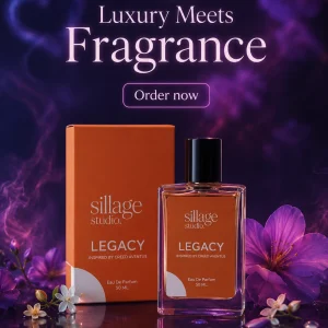 Sillage Studio Legacy Eau De Parfum 50ml glass bottle next to orange box on a reflective surface surrounded by purple flowers and smoke