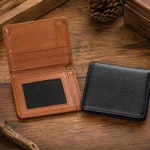 Open tan brown and folded black mini double fold leather wallets with ID window and card slots on rustic wooden background