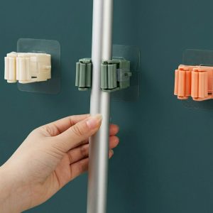 Self-adhesive wall mounted mop holder with non-slip roller grip securely holding a mop handle, ideal for organizing brooms and cleaning tools.